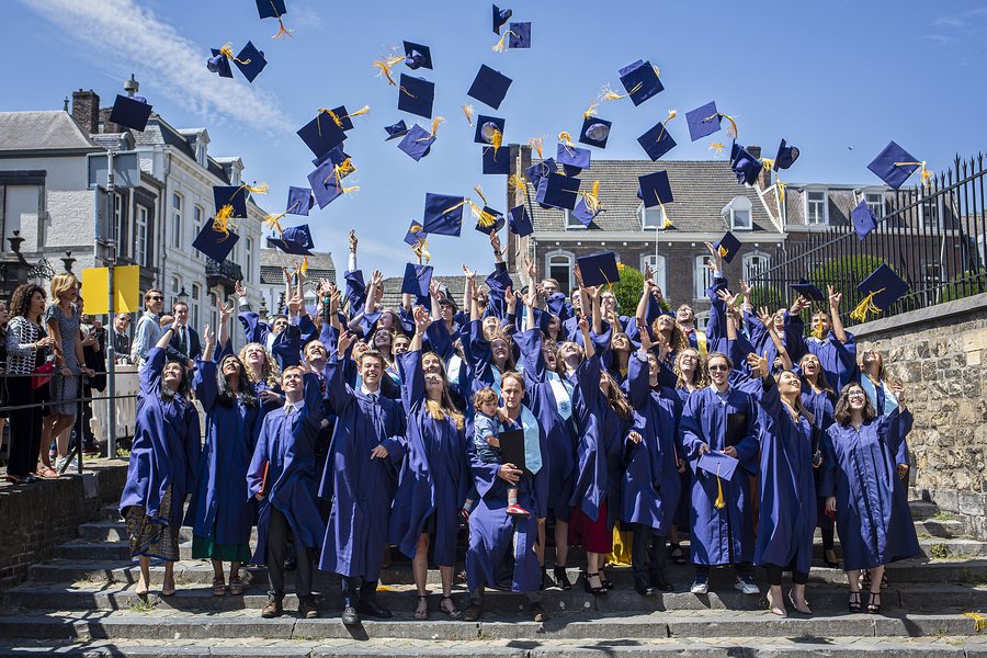 The class of 2019 on the steps, caps everywhere